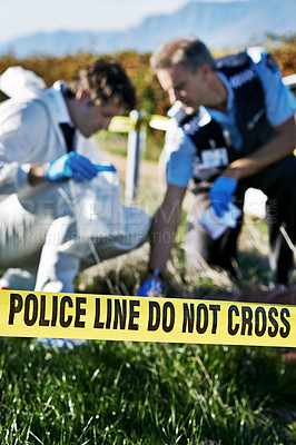 Buy stock photo Shot of two investigators collecting evidence at a murder scene
