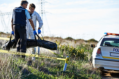 Buy stock photo Shot of two men carrying a body bag away from a crimescene