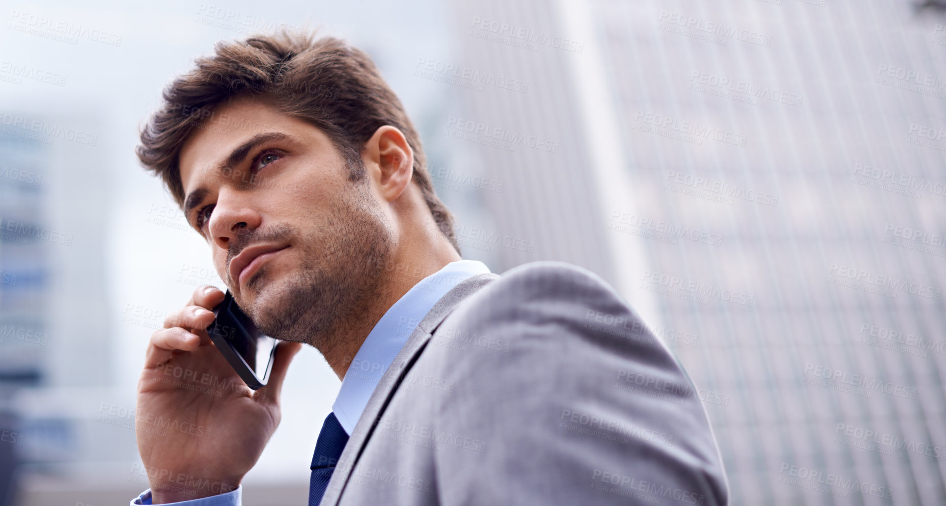 Buy stock photo A low angle shot of a handsome young businessman using his cellphone in the city