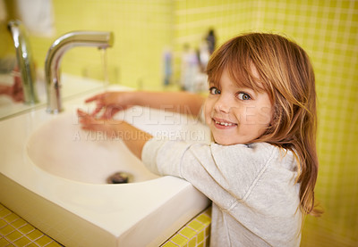 Buy stock photo A cute little girl washing her hands in the bathroom basin