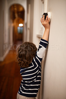 Buy stock photo A cropped shot of a little boy switching a light off in his home