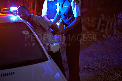 Buy stock photo Shot of a police officer handcuffing a suspect against his patrol car