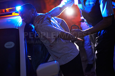 Buy stock photo Shot of a police officer handcuffing a suspect against his patrol car