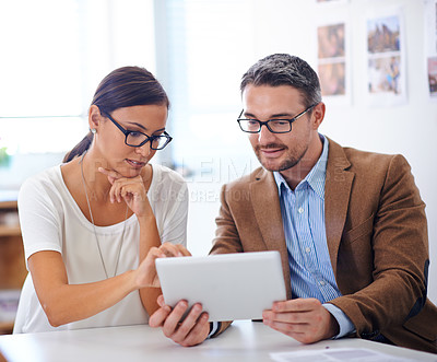 Buy stock photo Shot of two businesspeople using a tablet together