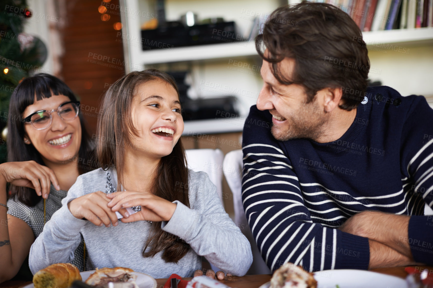 Buy stock photo Christmas, family and parents laugh with child in home for dinner, lunch and eating together. happy mother, father and girl with food for holiday, vacation and festive celebration at dining table