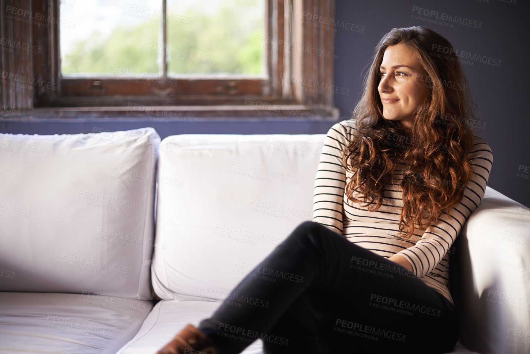 Buy stock photo Shot of an attractive woman sitting on her sofa