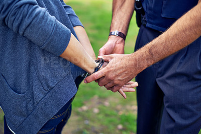 Buy stock photo Cropped shot of a policeman's hands putting cuffs on a suspect