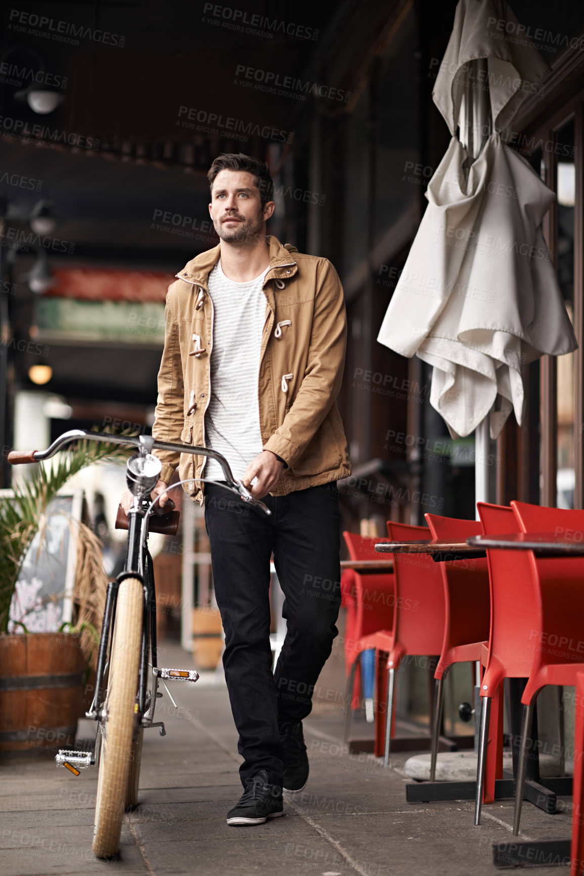 Buy stock photo Sidewalk, cafe and man with bicycle walking in city, thinking and eco friendly transport on commute. Carbon neutral, sustainability and tourist on street for urban journey, travel and male with bike