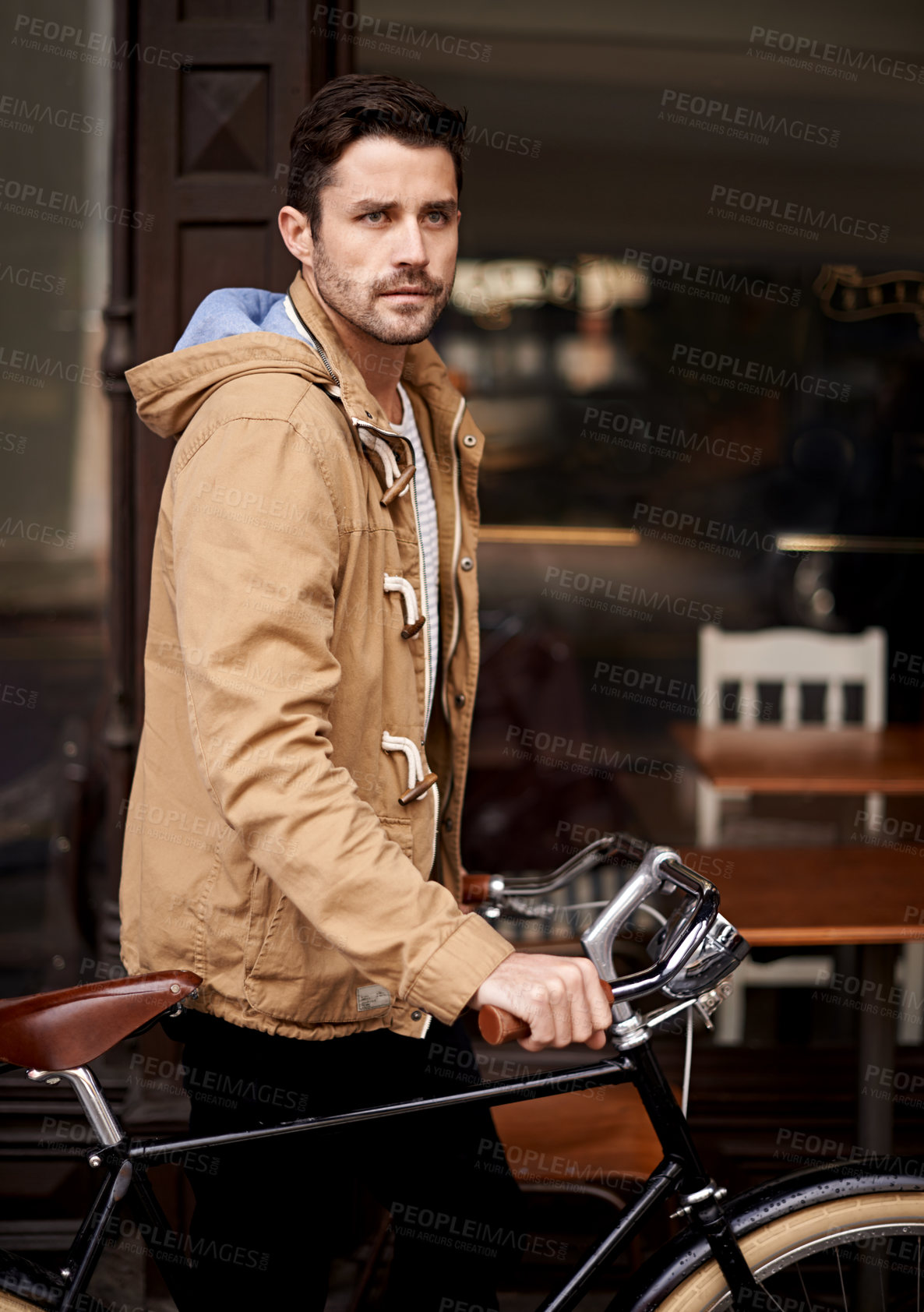 Buy stock photo Cropped shot of a young man pushing his bicycle