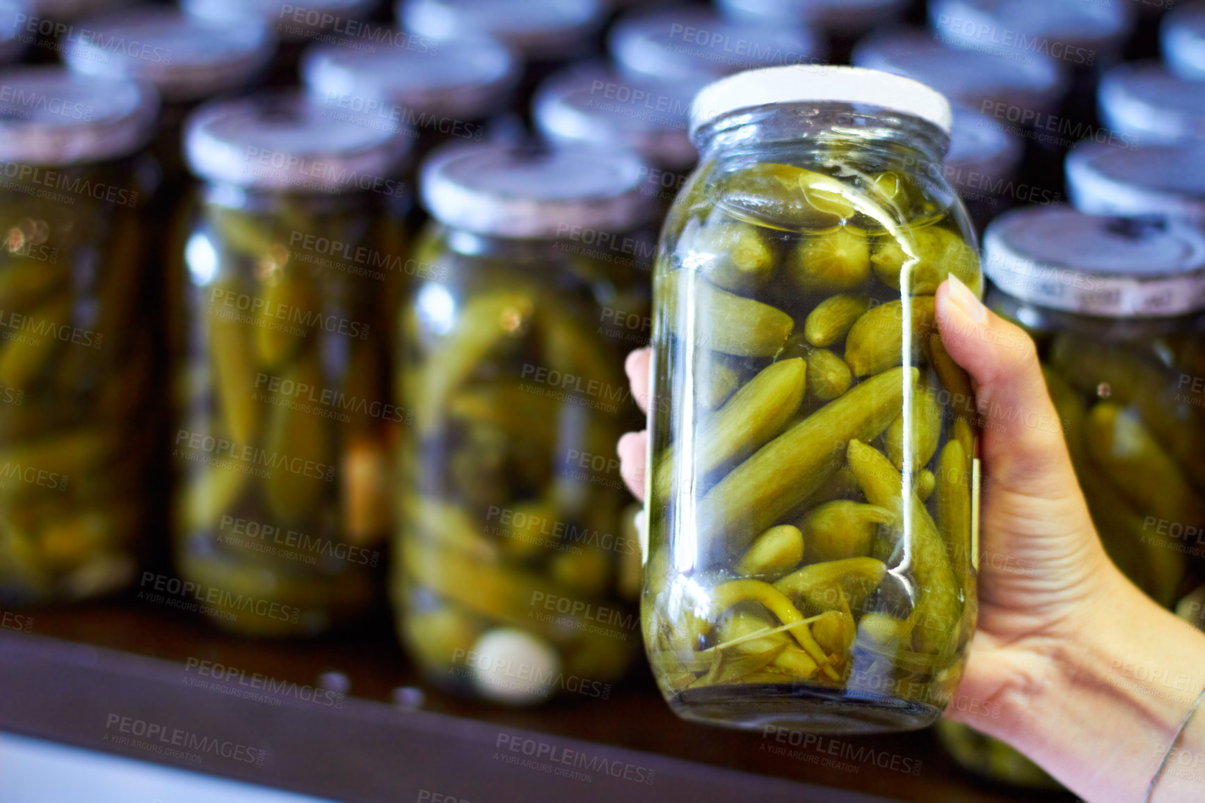 Buy stock photo Woman, hand and jar of pickles in store for product selection or choice, shelf and shopping for condiments. Person, gherkins and glass with vegetable in vinegar, organic and nutrition for health.