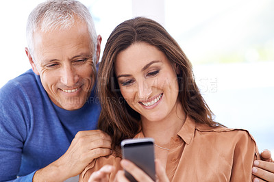 Buy stock photo Couple, smartphone and smile in home to relax with reading, search and mobile app for contact with bonding. People, woman and mature man with phone for notification, typing or web connection in house