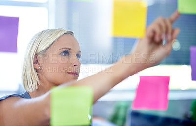 Buy stock photo Shot of a young woman in front of a transparent wall filled with post-its