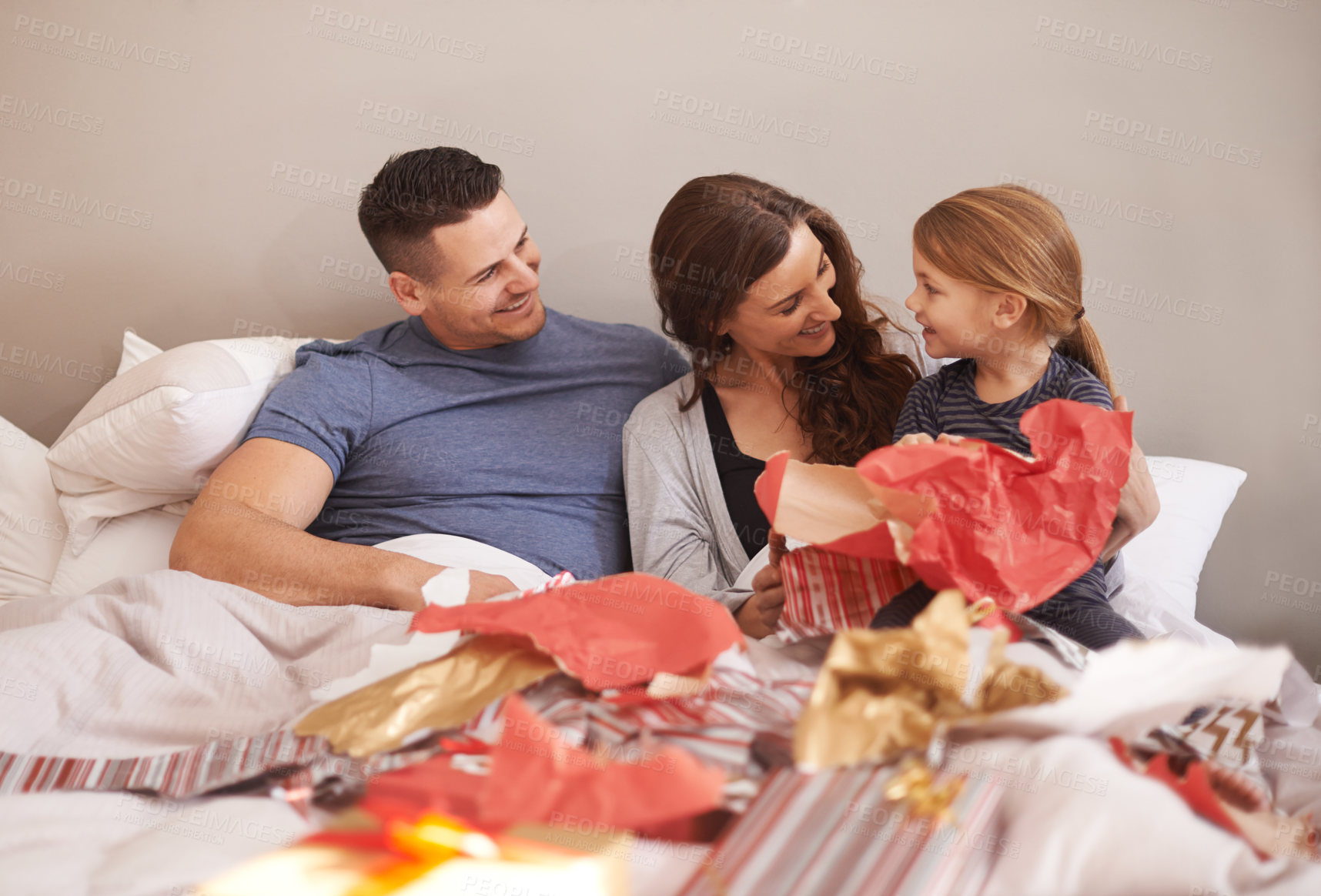 Buy stock photo Shot of a little girl receiving presents in bed from her parents