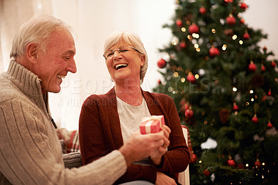 Buy stock photo Happy, love and old couple with a gift for Christmas in celebration of a spiritual celebration at home. Smile, surprise and senior woman enjoys giving fancy presents to an excited elderly partner