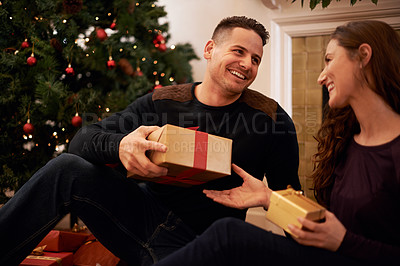 Buy stock photo A happy young couple opening presents on Christmas day