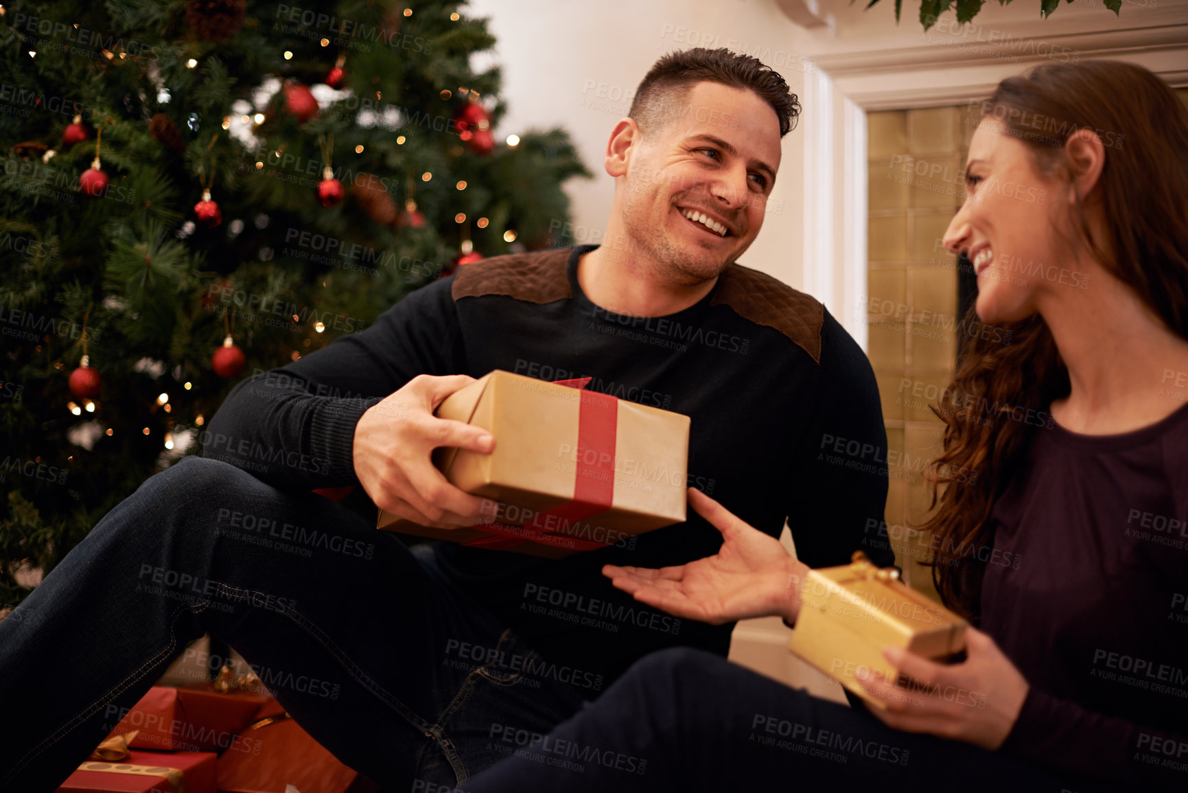 Buy stock photo A happy young couple opening presents on Christmas day