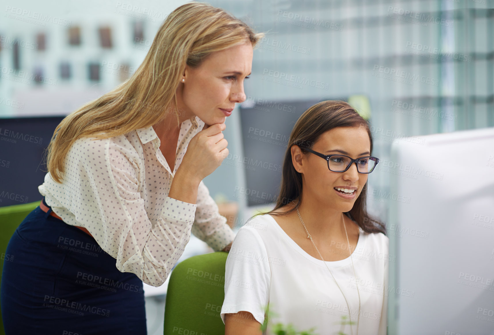 Buy stock photo Shot of two attractive female colleagues in a quandary over some work on a computer in an office setting