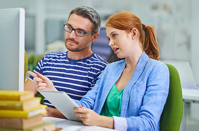 Buy stock photo Two coworkers sitting together brainstorming using a computer and digital tablet at work