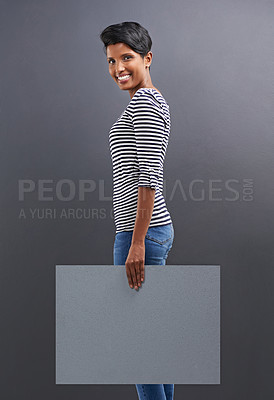 Buy stock photo Happy woman, portrait and presentation with billboard for marketing or advertising on a gray studio background. Young female person or Indian with smile, poster or sign for message on mockup space