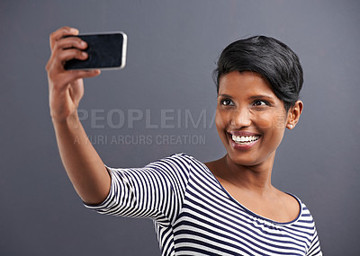 Buy stock photo Studio shot of a beautiful young woman taking a selfieagainst a grey background