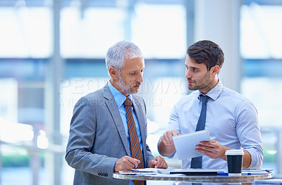 Buy stock photo Shot of a young businessman with a tablet discussing work with his colleague