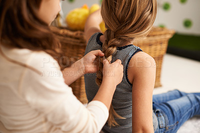 Buy stock photo Rearview shot of a little girl braiding her sister's hair at home