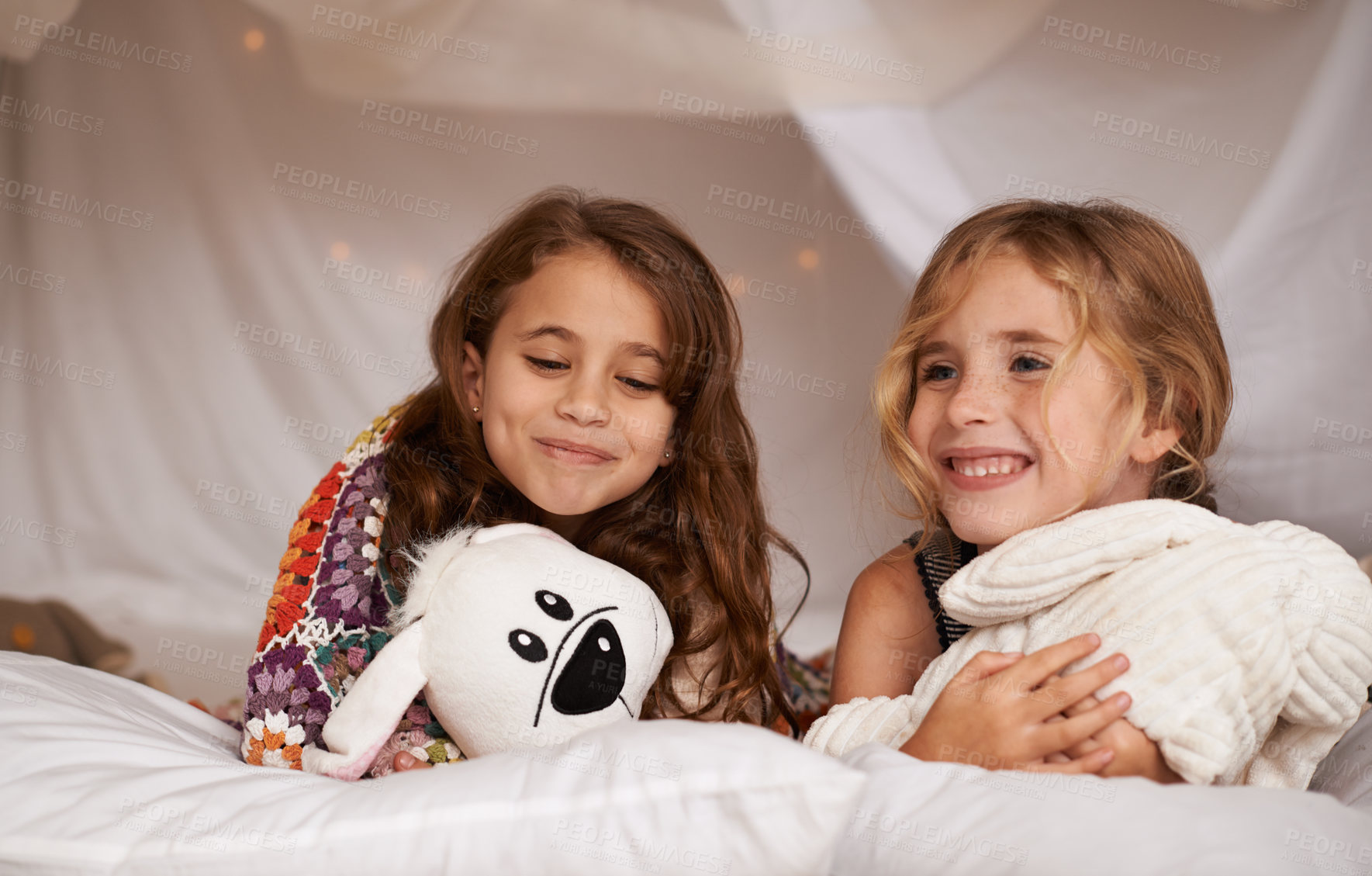 Buy stock photo Happy, sleepover and children in bedroom for playing, bonding and relax with toys in home. Night, friends and young girls on bed in tent or blanket fort for childhood, fun and happiness together