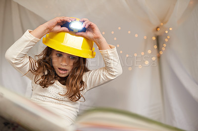 Buy stock photo Girl, child and book for reading with lamp, below and learning with thinking for education in family home. Kid, story and study with light on helmet, language or literacy skills with blanket in house