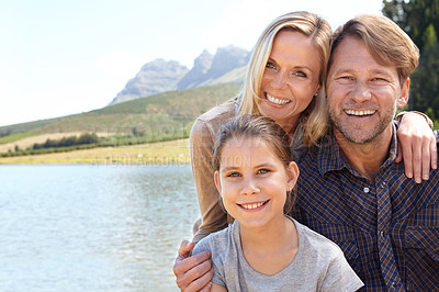 Buy stock photo Portrait of a happy family of three sitting together at a lake