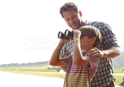 Buy stock photo Shot of a young boy and his father bird-watching nearby a lake