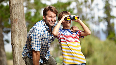 Buy stock photo Father, son and binoculars in forest for outdoor adventure, birdwatching or learning by trees with smile. Dad, child and hug for vision, view and search for connection, care and bonding in woods