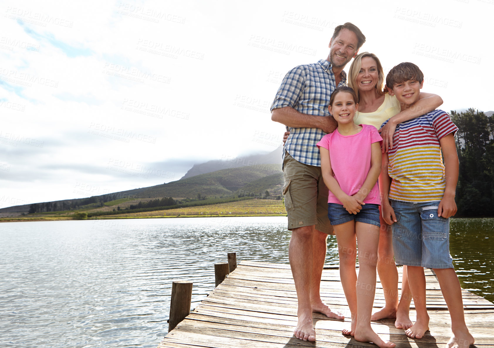 Buy stock photo Family, portrait by lake and outdoor on pier for travel with vacation, parents and kids with fresh air in nature for bonding. Love, support and trust, happy people and adventure together with smile