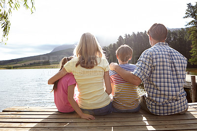 Buy stock photo Rear view shot of a family sitting on a pier out on a lake in the countryside