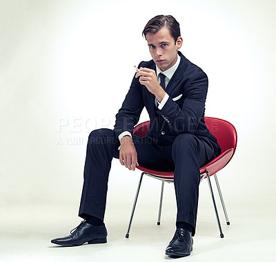 Buy stock photo A studio portrait of a handsome young gentleman in a pinstripe suit sitting on a chair