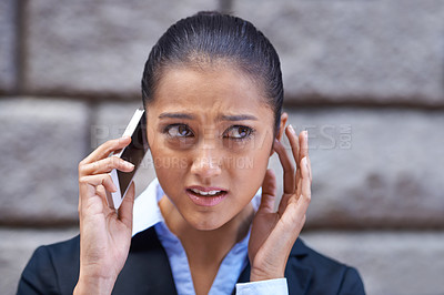 Buy stock photo A shot of a young businesswoman having trouble hearing on her cellphone