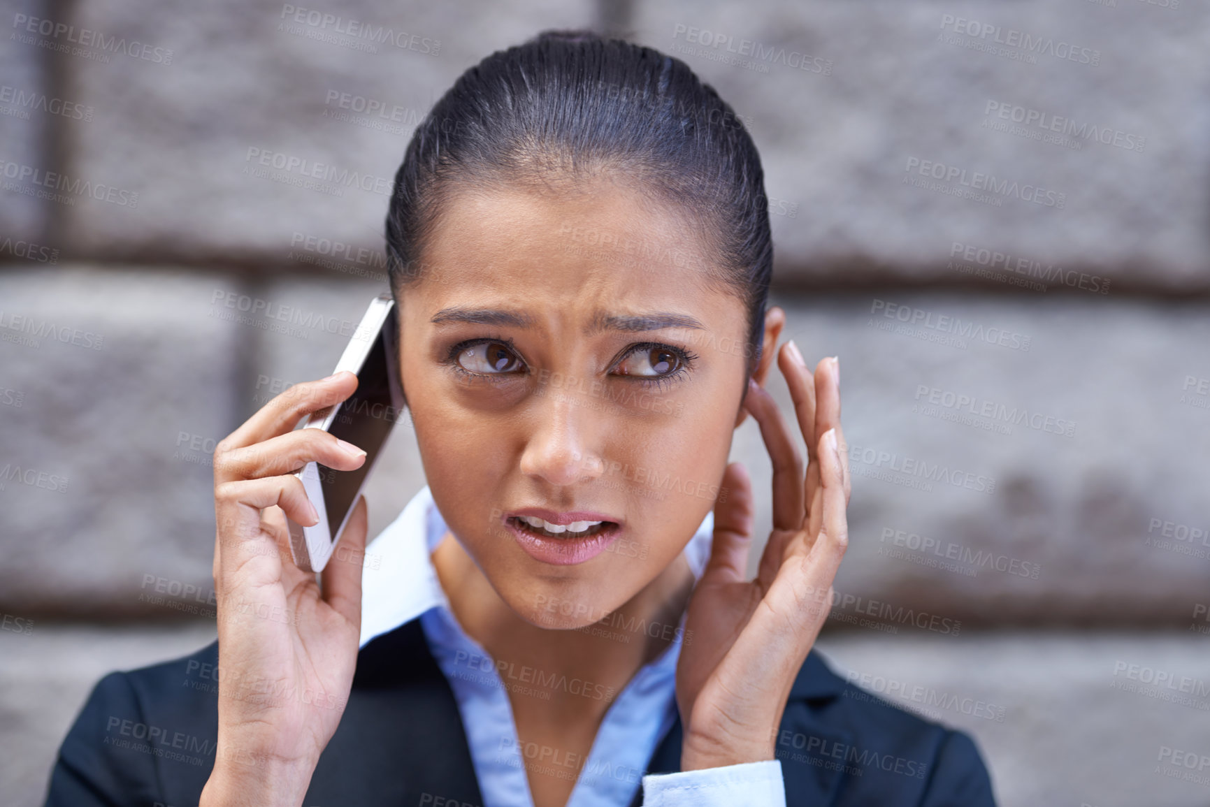 Buy stock photo A shot of a young businesswoman having trouble hearing on her cellphone