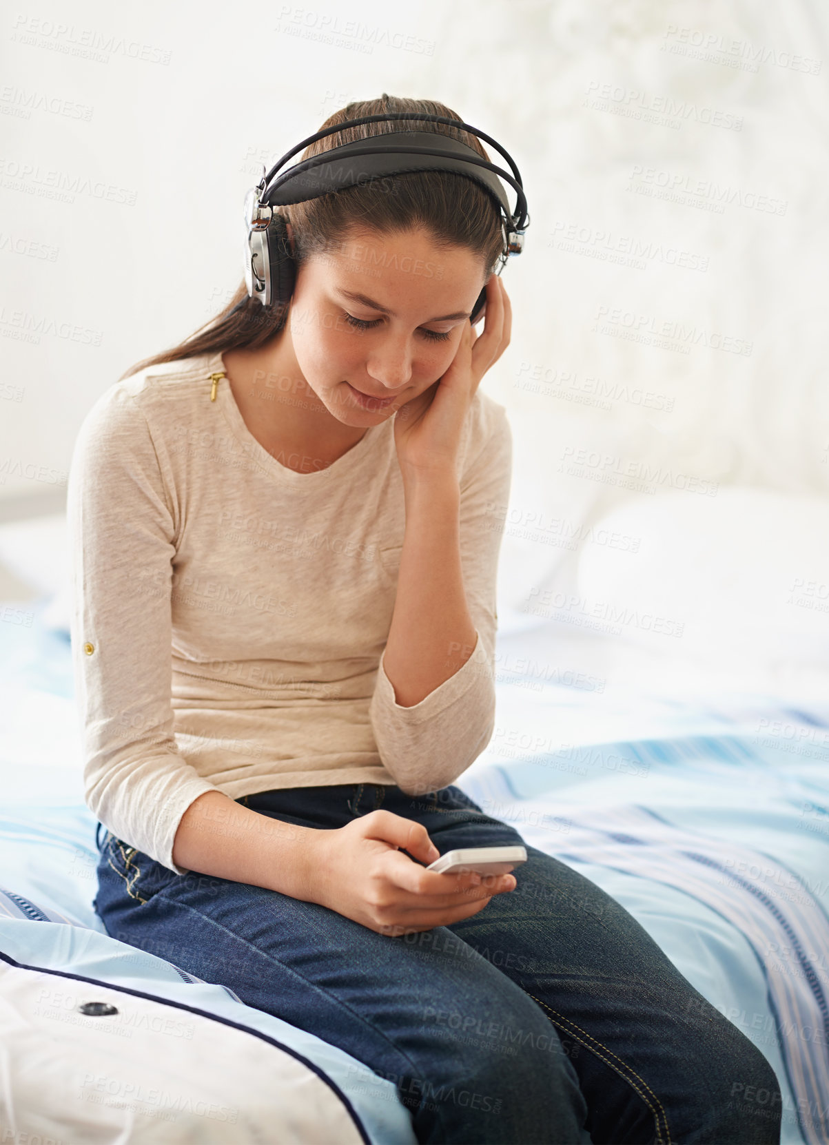 Buy stock photo Headphones, phone and teenager listening to music on bed to relax with streaming on mobile app. Bedroom, girl and kid with technology for podcast, online and connection to internet for audio