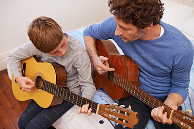Buy stock photo Shot of a father teaching his son the guitar