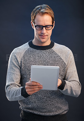 Buy stock photo Man, glasses and tablet for reading in studio with connection, contact and fashion by dark background. Person, entrepreneur and digital touchscreen, pride and confidence with app for social network