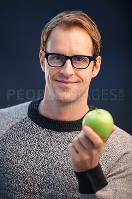 Buy stock photo Man, apple and glasses in studio portrait with smile for choice, diet or health by dark background. Person, model and happy with green fruit with  pride for decision, vegan nutrition or organic snack