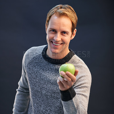 Buy stock photo Man, apple and smile in studio portrait with choice for detox, diet or health by dark background. Person, model and happy with green fruit with pride for decision, vegan nutrition and organic snack