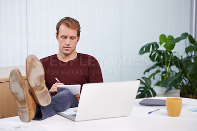 Buy stock photo Office, man and relax at desk with notes from laptop for research work for project or task, feet up and writing on notepad. Male person, computer and writing information for creative company work.