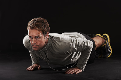 Buy stock photo Man, face and push up with fitness or music in studio with exercise, workout and training with earphones. Athlete, person and bodybuilder on floor with audio, radio and podcast on black background