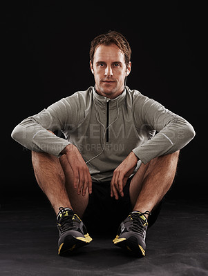 Buy stock photo Break, portrait or runner in studio for fitness, running workout or exercise for health wellness. Tired, athlete and sports man sitting in training to relax for fatigue isolated on black background
