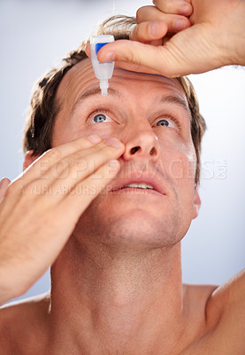 Buy stock photo Cropped studio shot of a man adding eye drops to his eyes