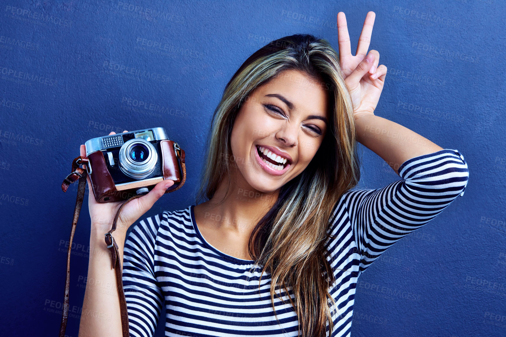 Buy stock photo Cropped shot of a playful young woman holding a camera