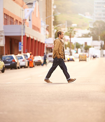 Buy stock photo Full lenth shot of a casually dressed man walking across the street
