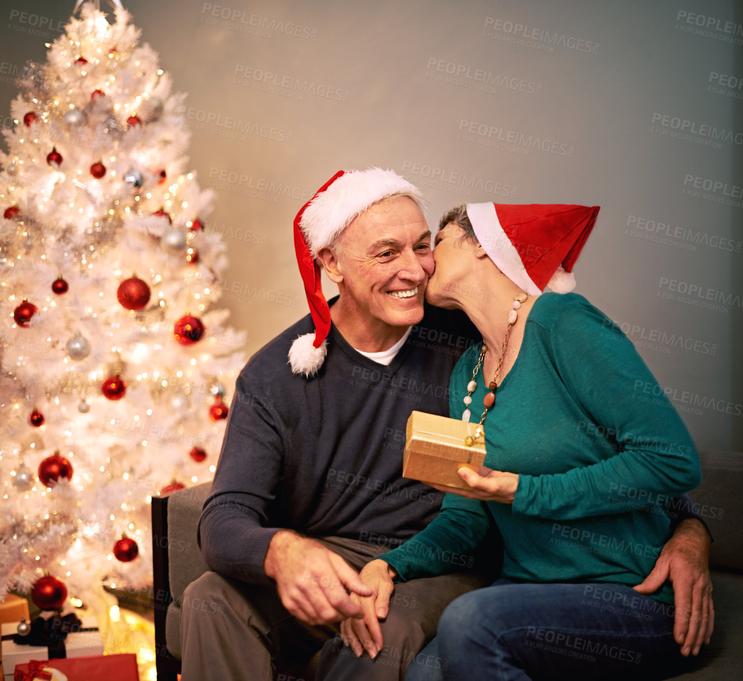 Buy stock photo A happy mature couple exchanging Christmas gifts in front of their Christmas tree