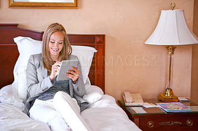 Buy stock photo A young businesswoman using a digital tablet in a bedroom