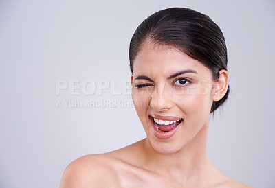 Buy stock photo Excited woman, portrait and wink with skincare in satisfaction for beauty, cosmetics or facial treatment on a gray studio background. Happy female person, brunette or model flirting on mockup space